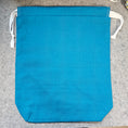 Load image into Gallery viewer, Dark turquoise drawstring bag with white string on a gray surface.
