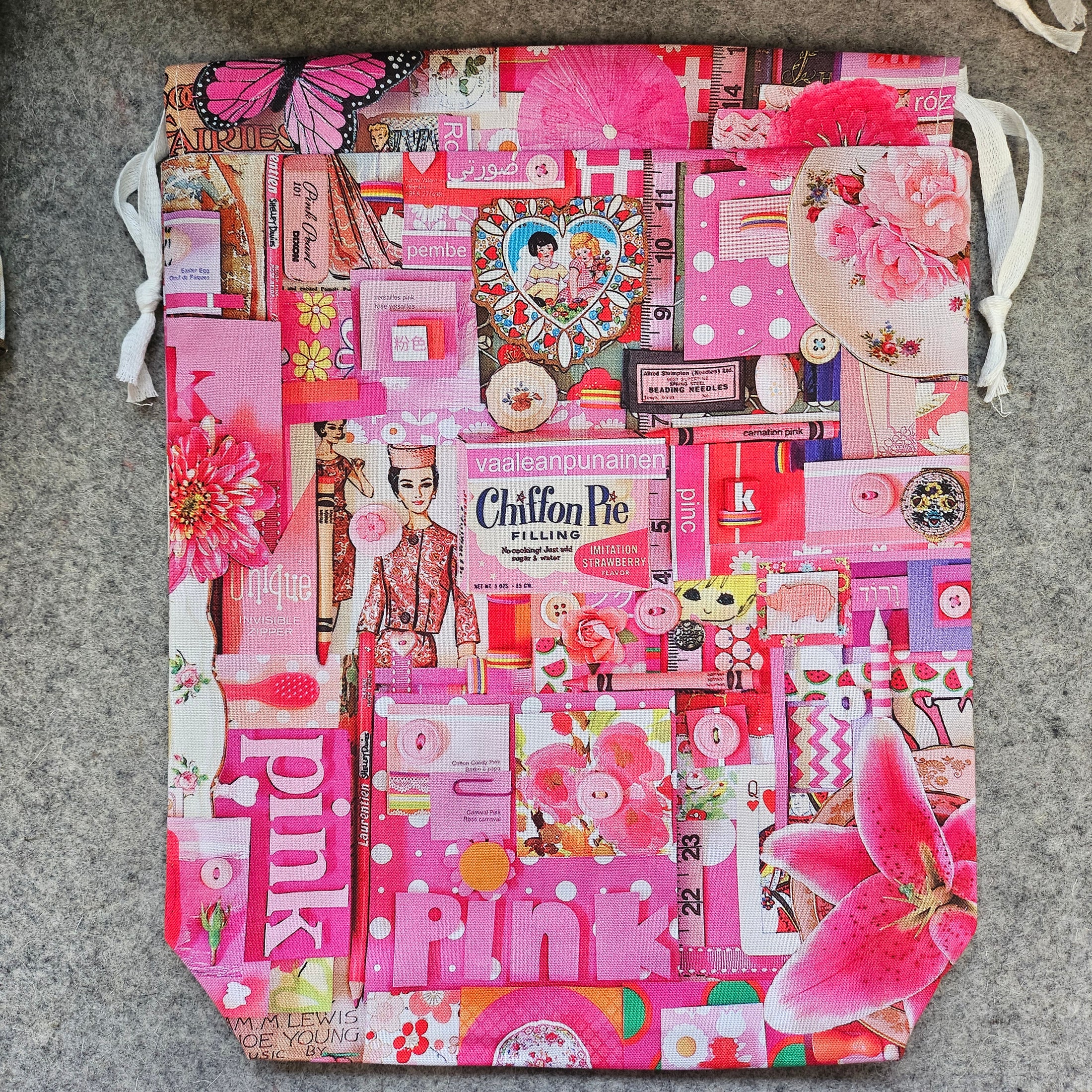 Pink-themed tote bag with various patterns and text on a gray surface