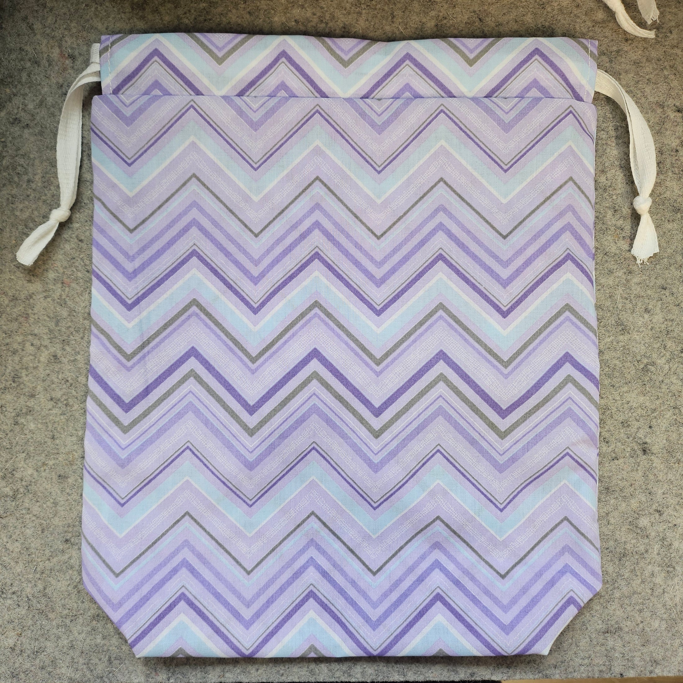 Purple chevron drawstring bag with white strings.