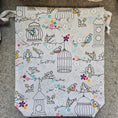 Load image into Gallery viewer, Light gray drawstring bag with birdcages and birds.
