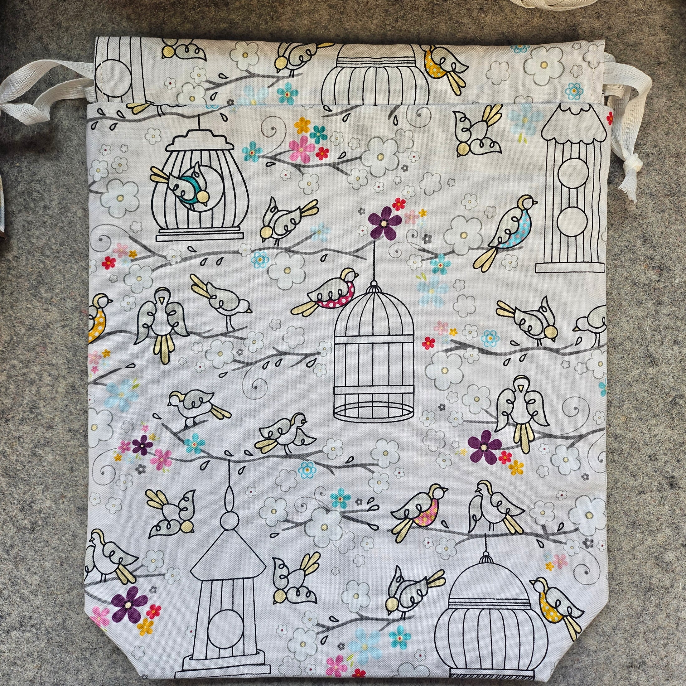 Light gray drawstring bag with birdcages and birds.