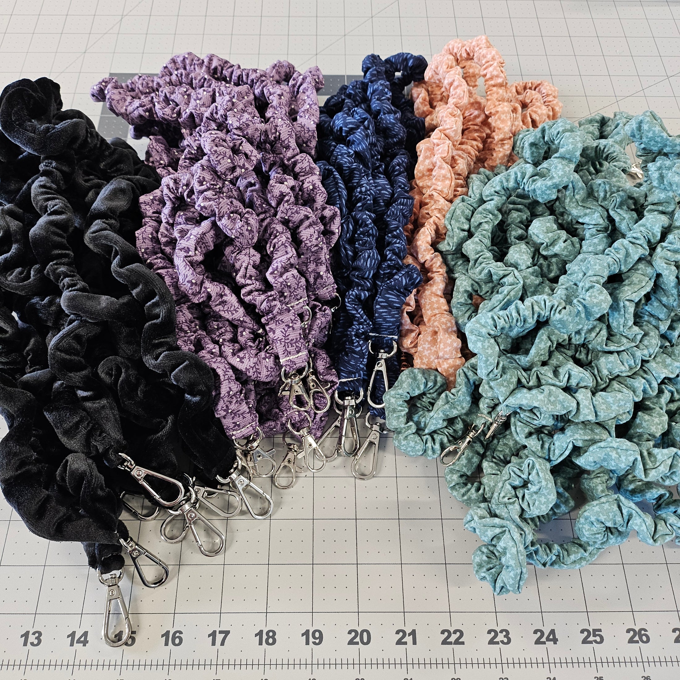 Assorted colors of skinny scrunchie lanyards laying on a cutting mat.