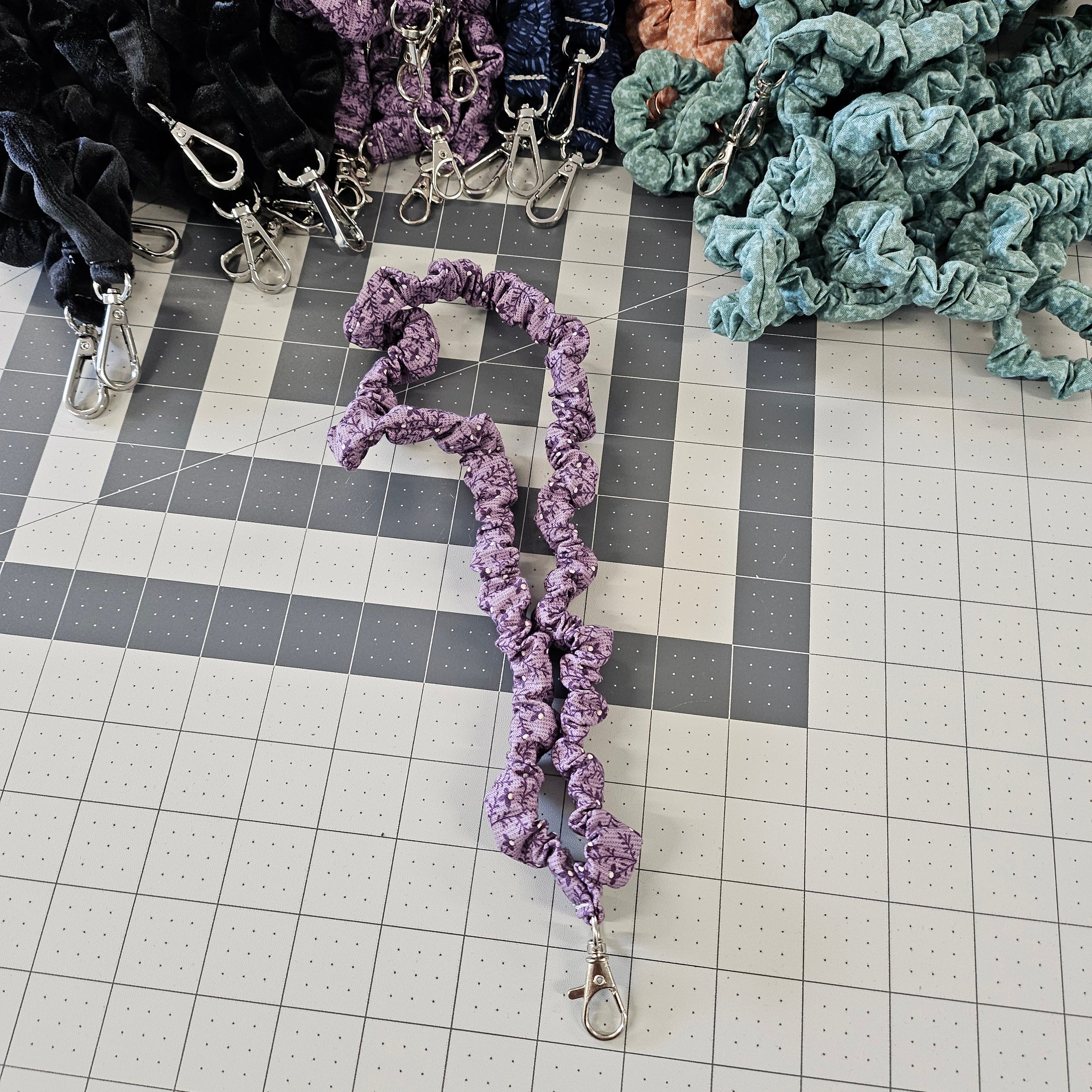 Purple skinny scrunchie lanyard laying on a gray cutting mat.