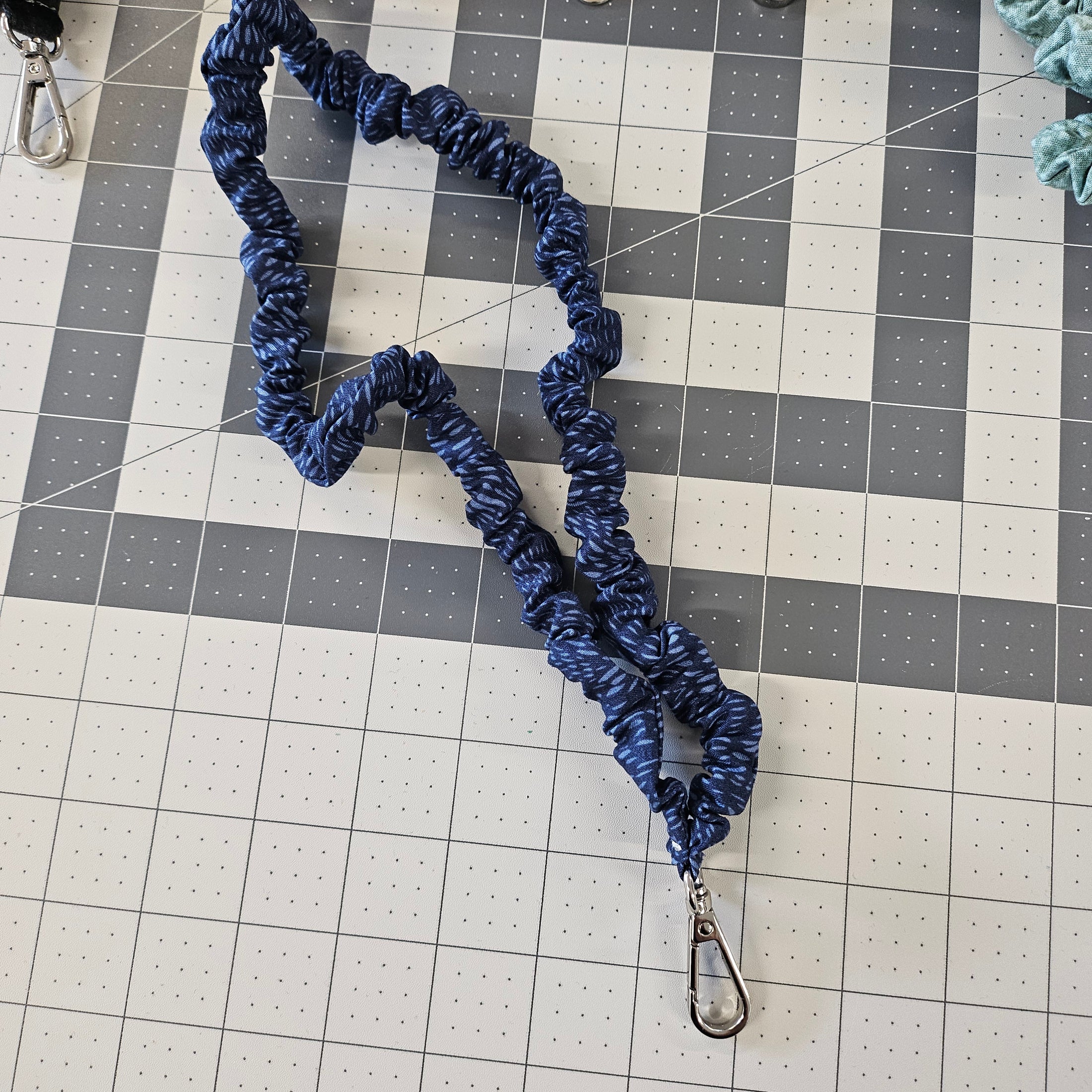 Dark blue skinny scrunchie lanyard laying on a gray cutting mat.