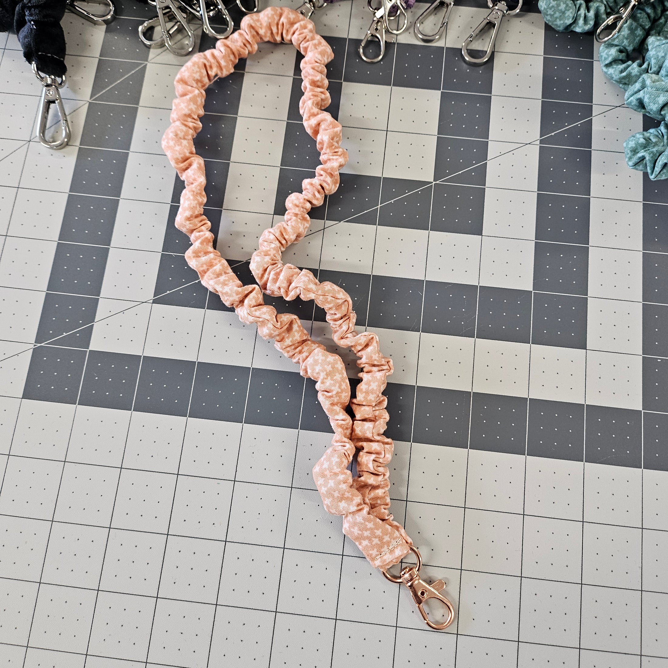 Peach skinny scrunchie lanyard laying on a gray cutting mat.