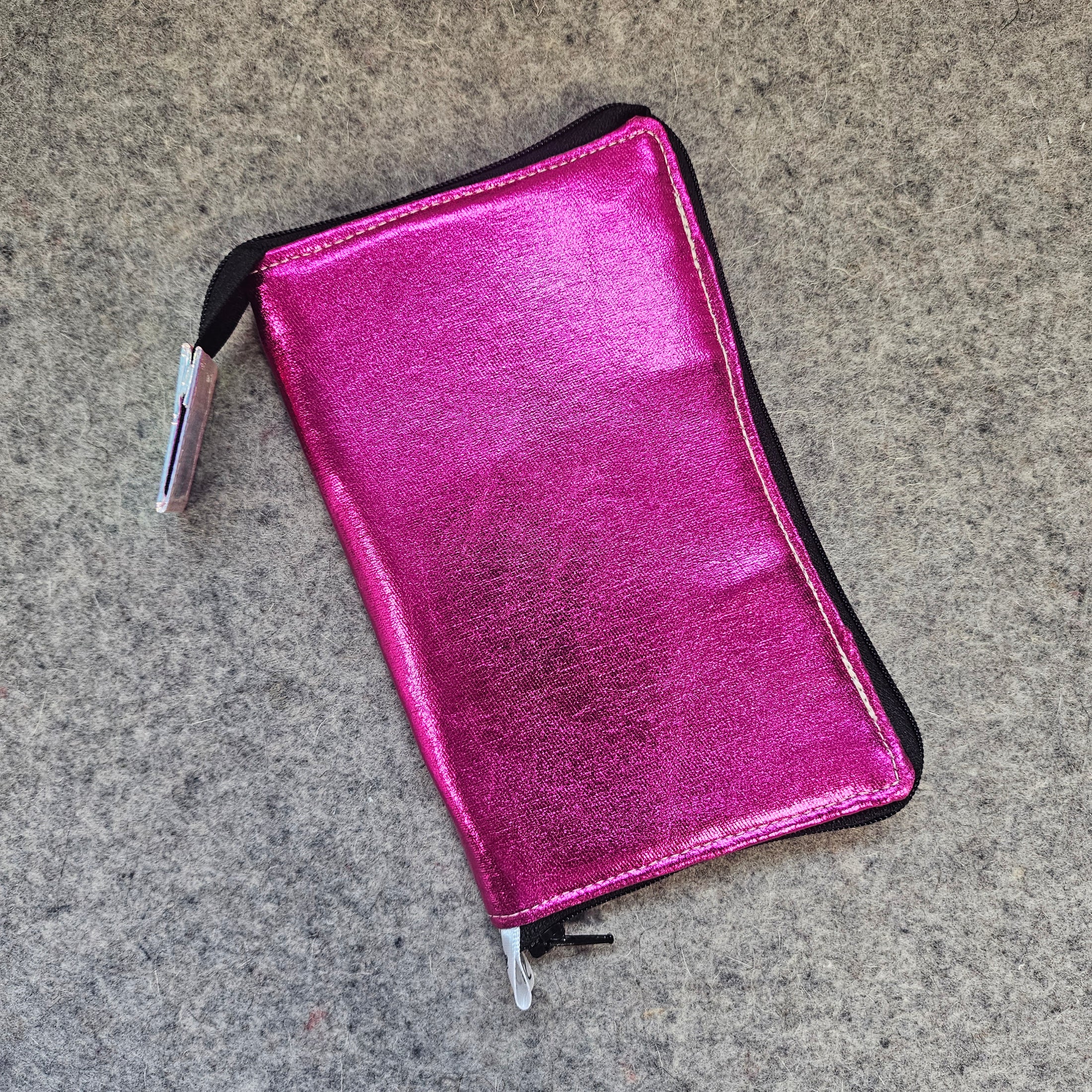 Pink metallic wallet on a gray concrete surface