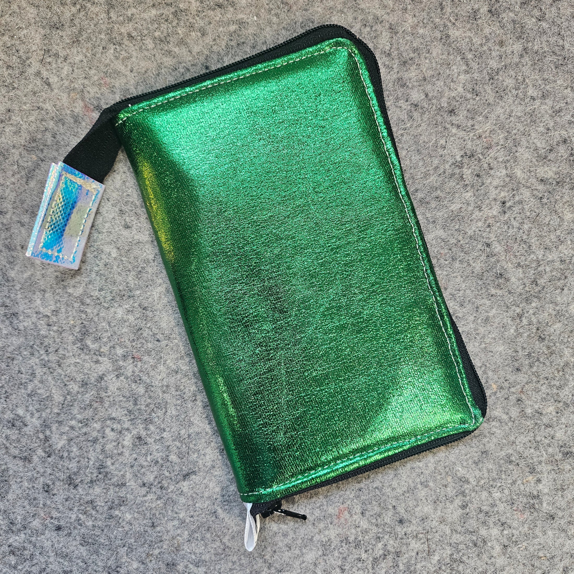 Green metallic wallet with a small card on a gray surface