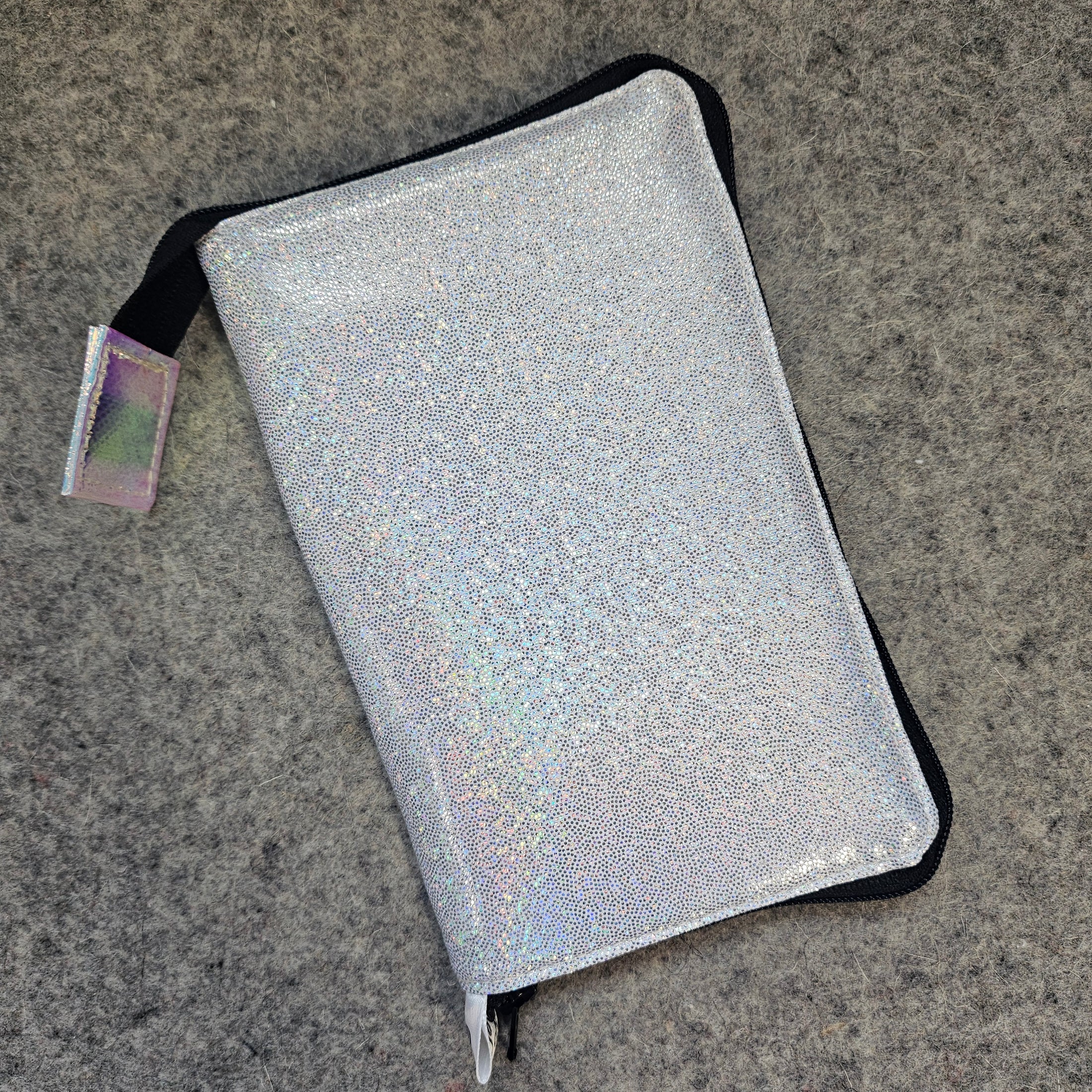 Silver glittery pouch with a strap on a gray surface