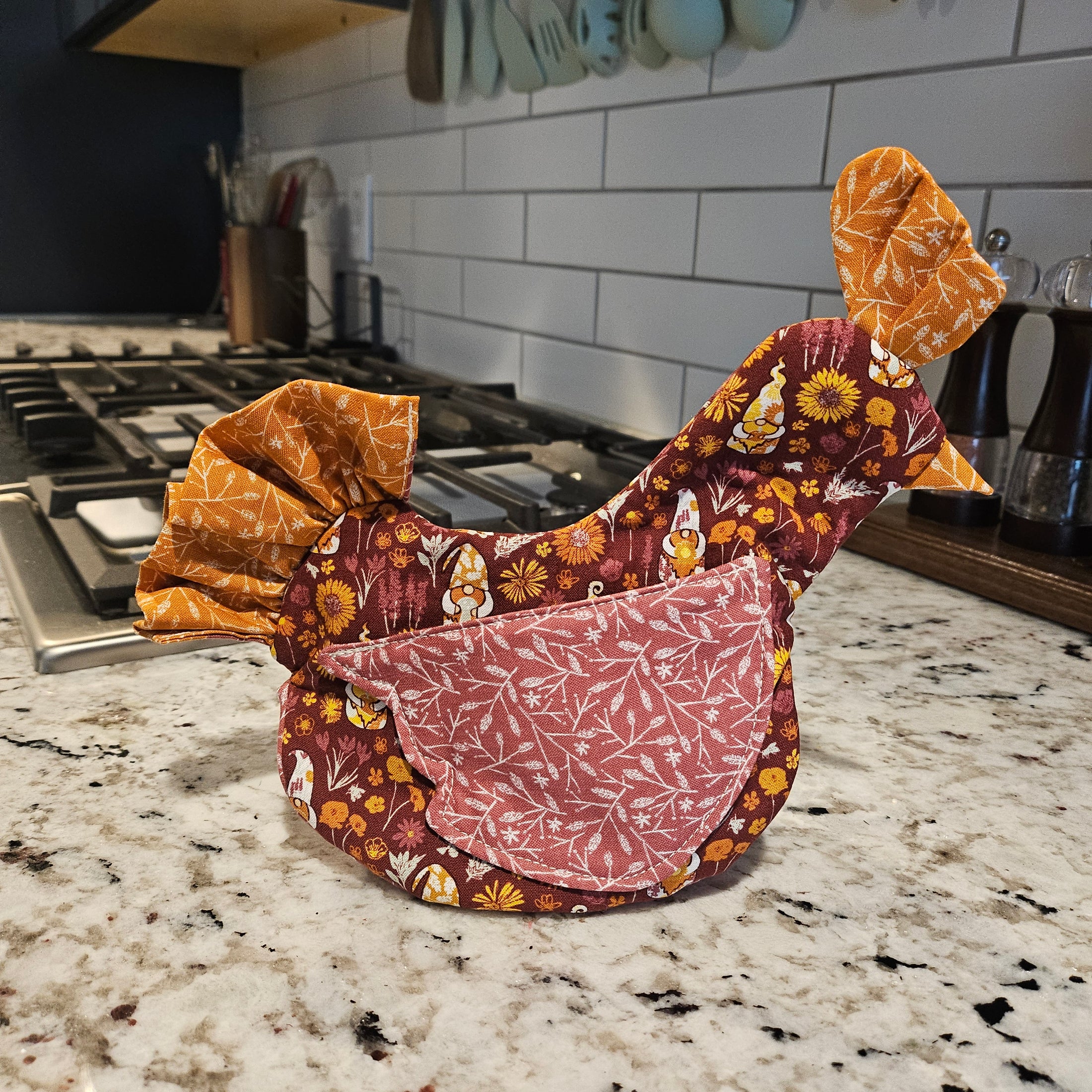 Decorative oven mitt with floral patterns on a kitchen counter.