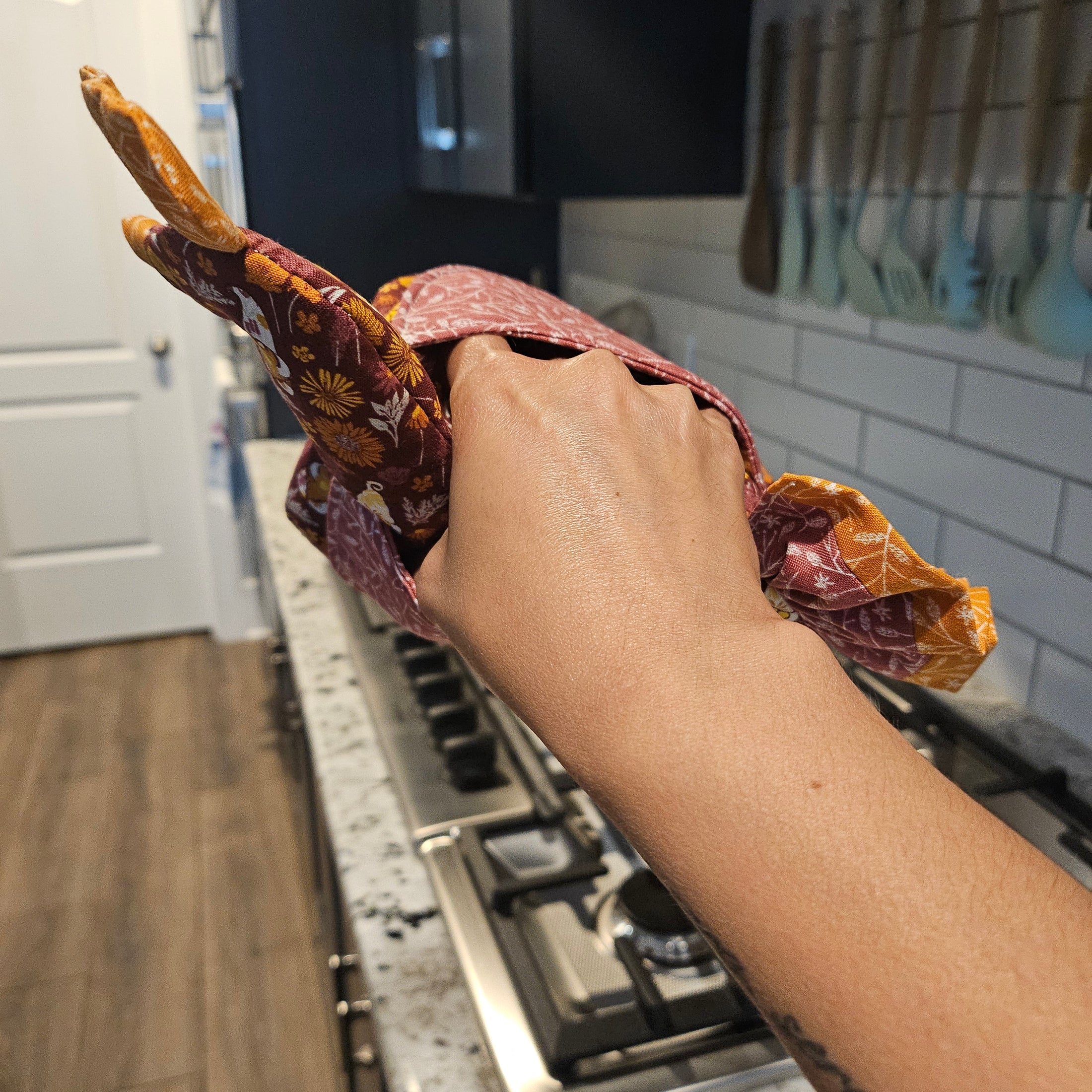 Person holding a piece of food wrapped in paper with a kitchen background