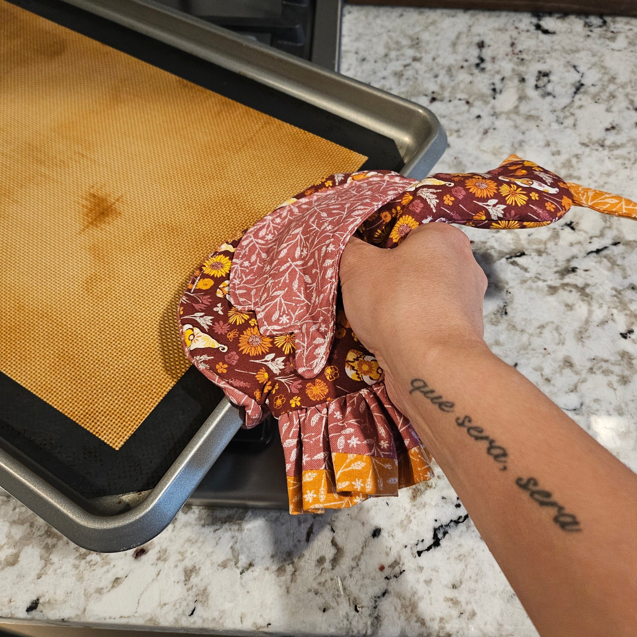 Hand holding a floral-patterned bag over a grill on a marble surface