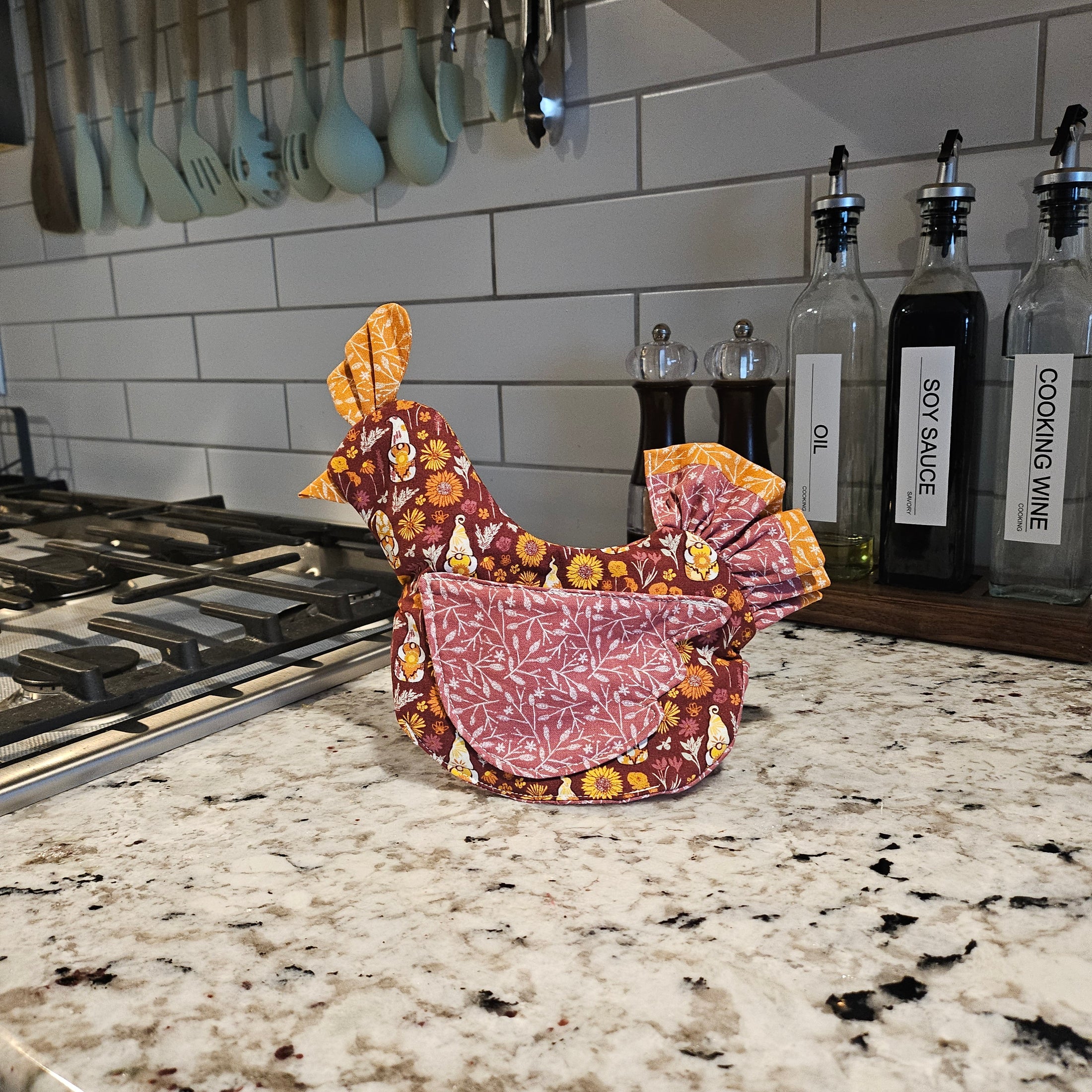 Decorative headscarf with floral patterns on a kitchen counter next to bottles of cooking wine, soy sauce, and oil.