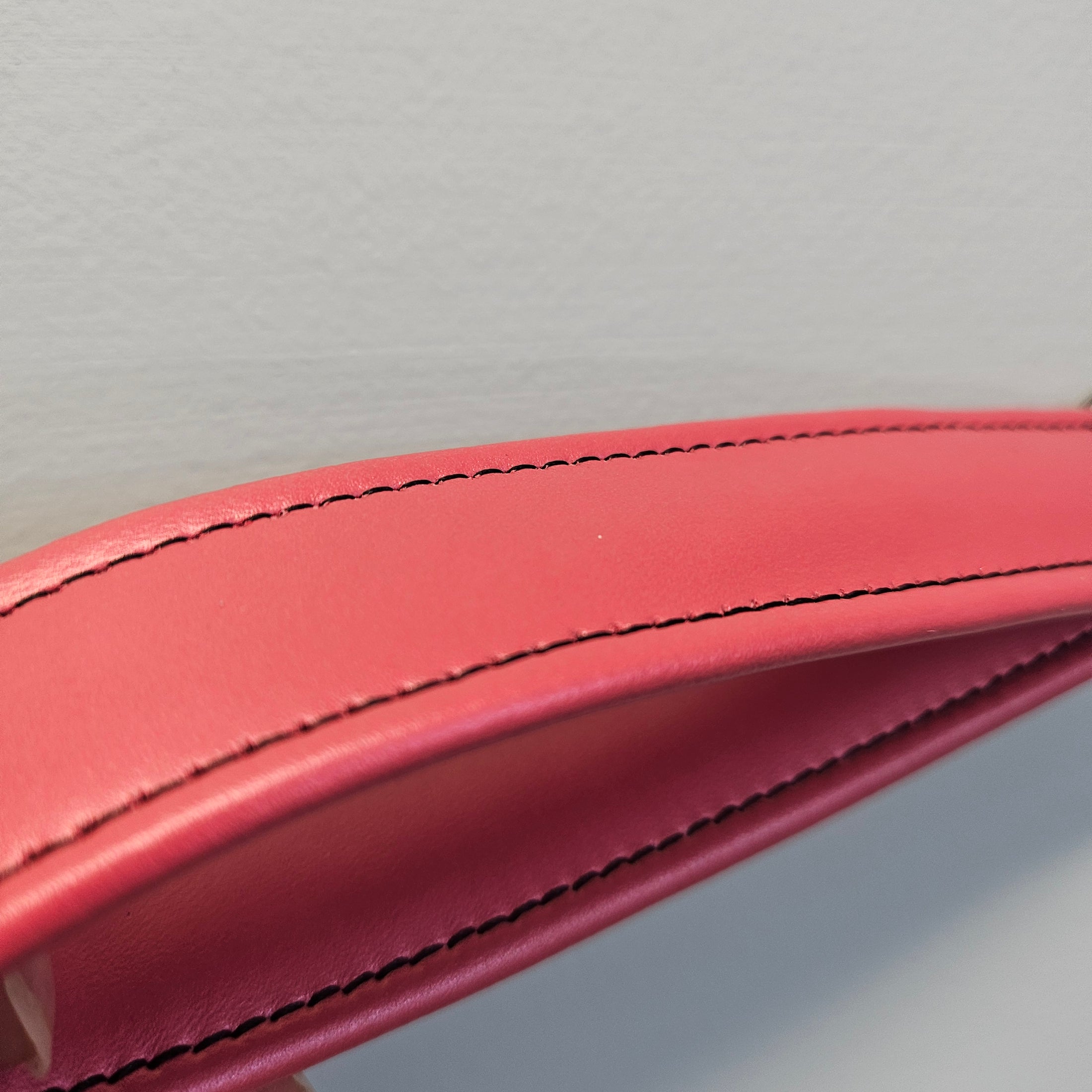 Close-up of a red leather product with visible stitching on a light gray background