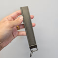 Load image into Gallery viewer, Hand holding a gray keychain strap against a light gray background
