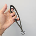 Load image into Gallery viewer, Hand holding a pair of blacksmith-made tongs against a light gray background
