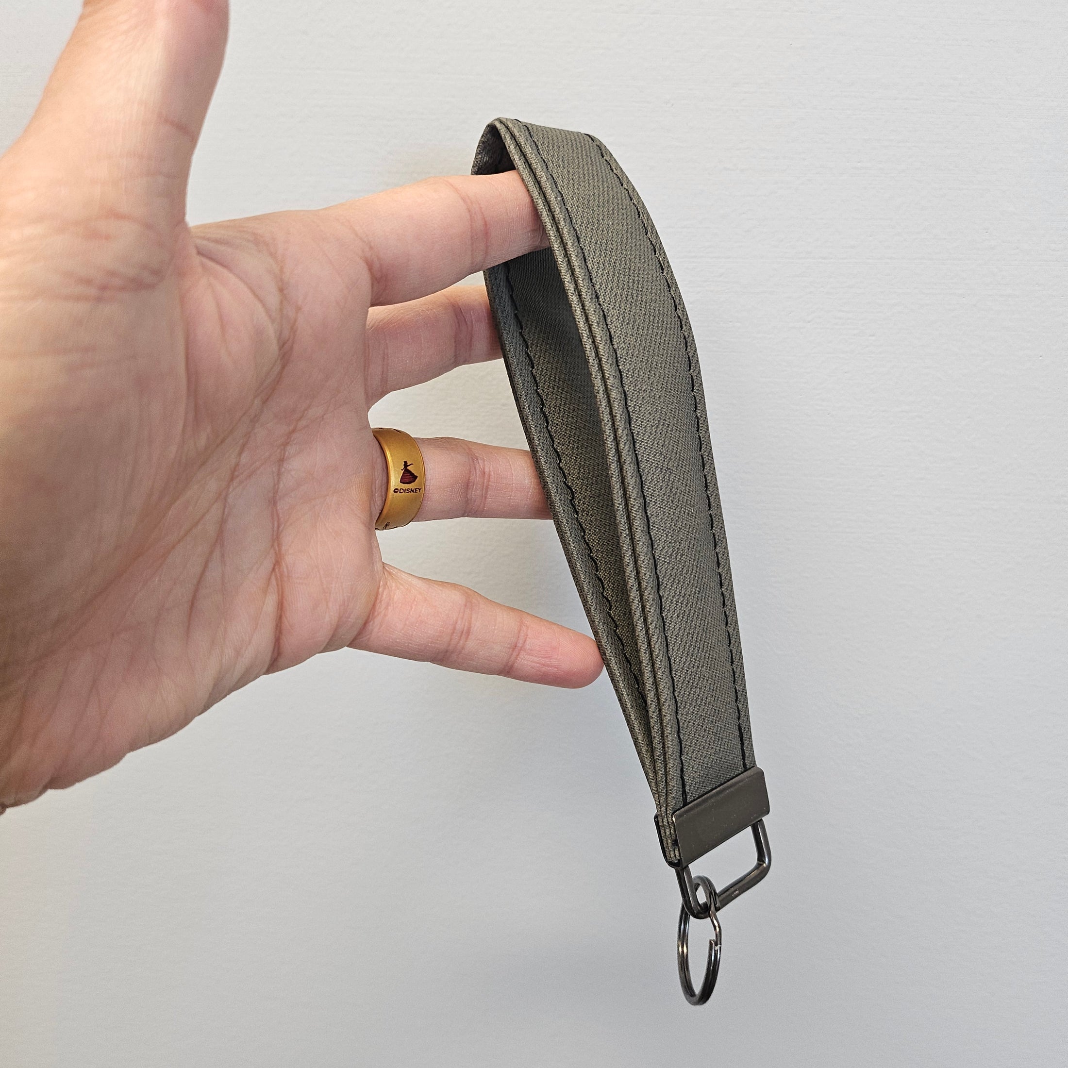Hand holding a green belt strap against a light gray background