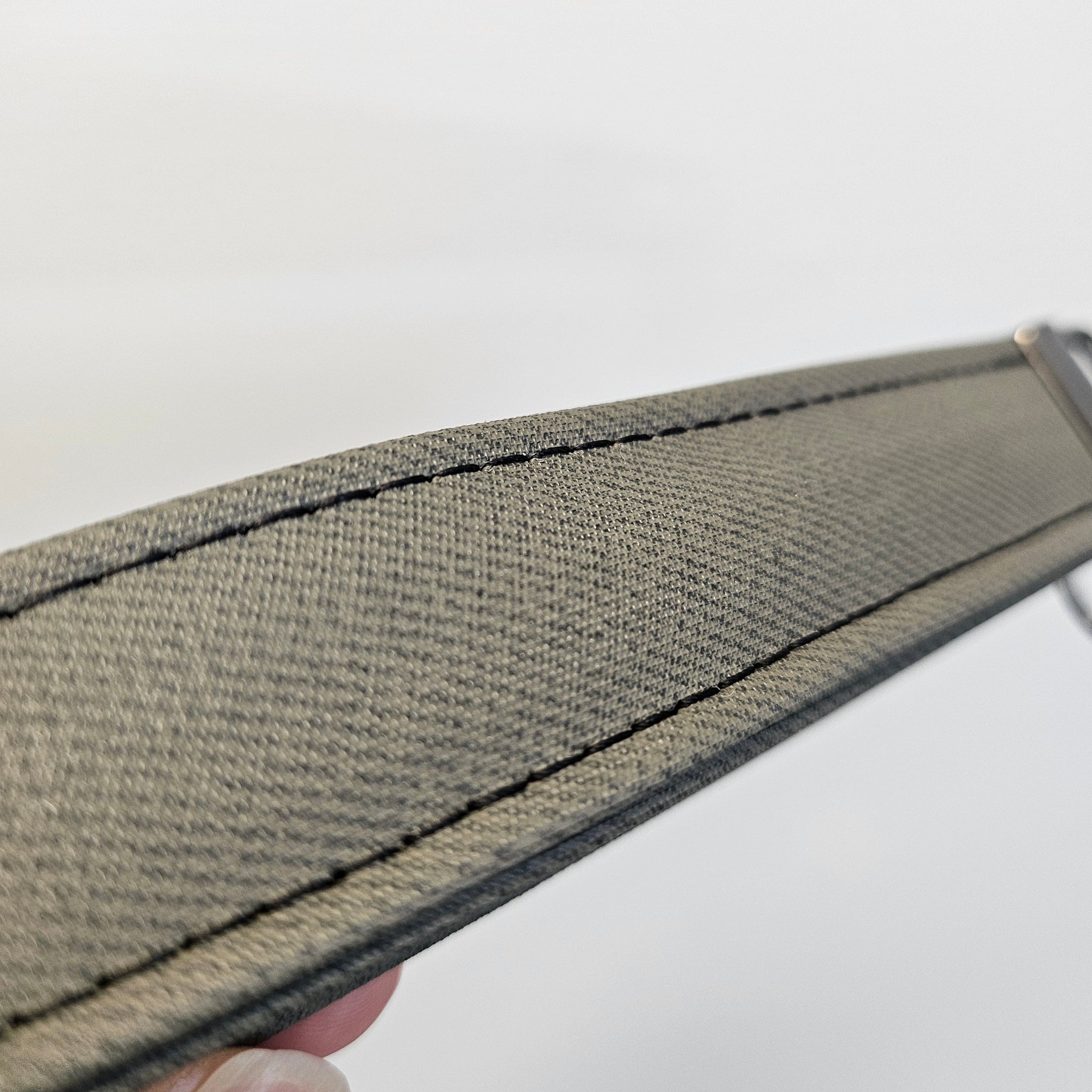 Close-up of a textured gray strap with stitching on a white background