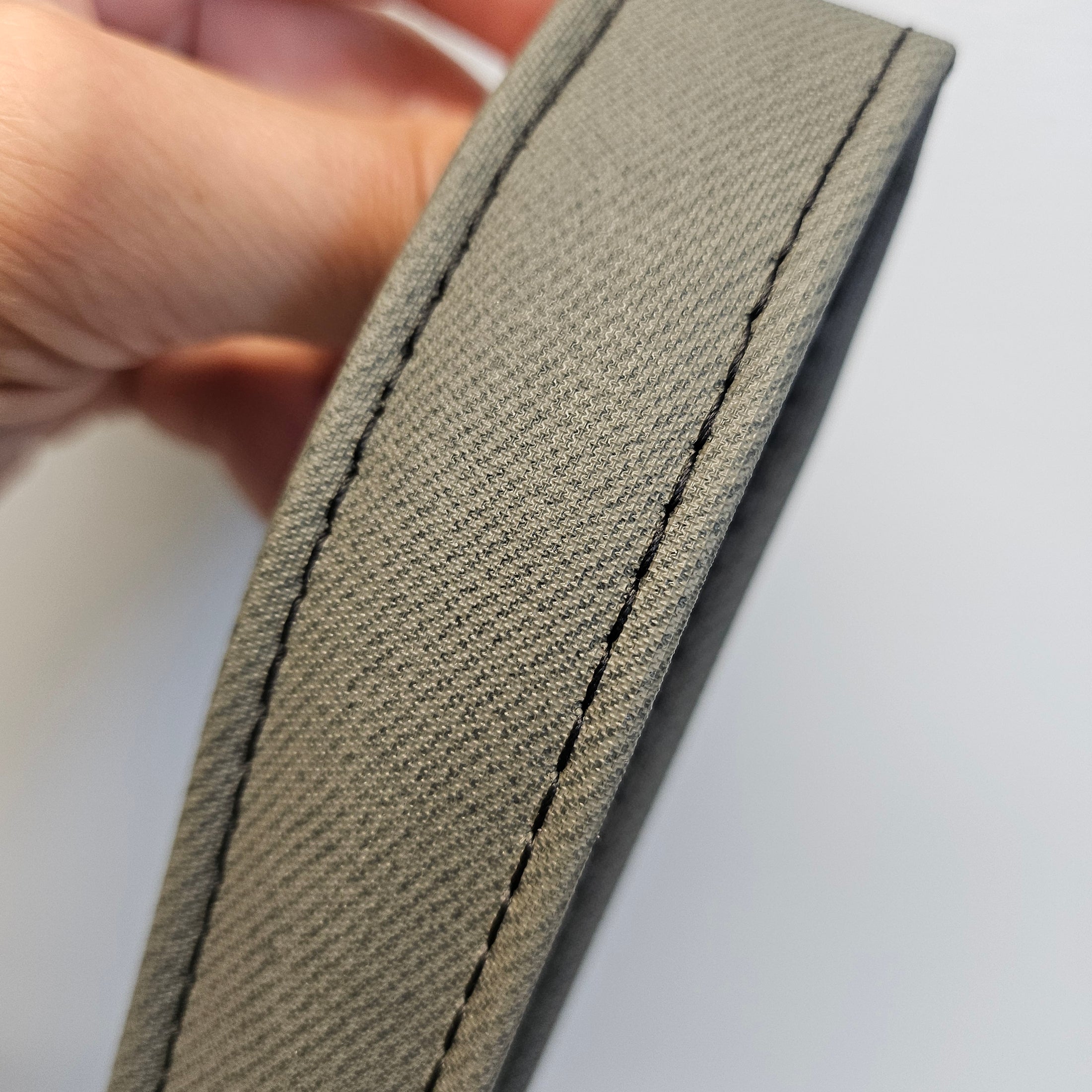 Close-up of a beige fabric strip held by a hand against a white background