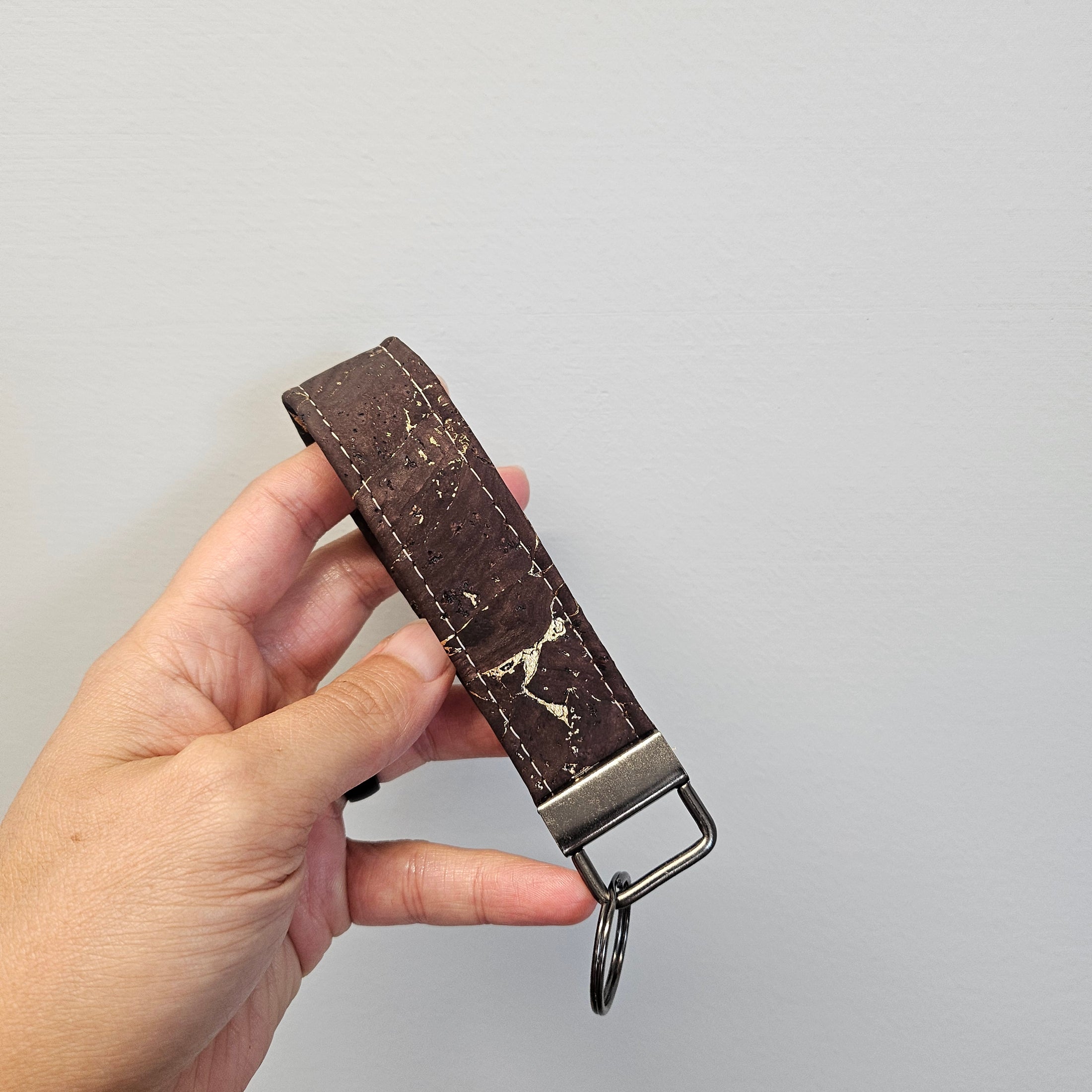 Gold and brown cork key fob against a light gray wall.