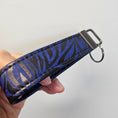 Load image into Gallery viewer, Blue and black cork key fob against a light gray background.
