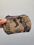 Load image into Gallery viewer, A hand holding a small zippered pouch with a vintage-style zombie illustration print on a light gray background.
