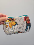 Load image into Gallery viewer, A hand holding a small zippered pouch with a colorful zombie illustration on a light gray background.
