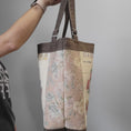 Load image into Gallery viewer, Side of the vintage flower seed tote bag featuring a muted floral fabric and brown accents.
