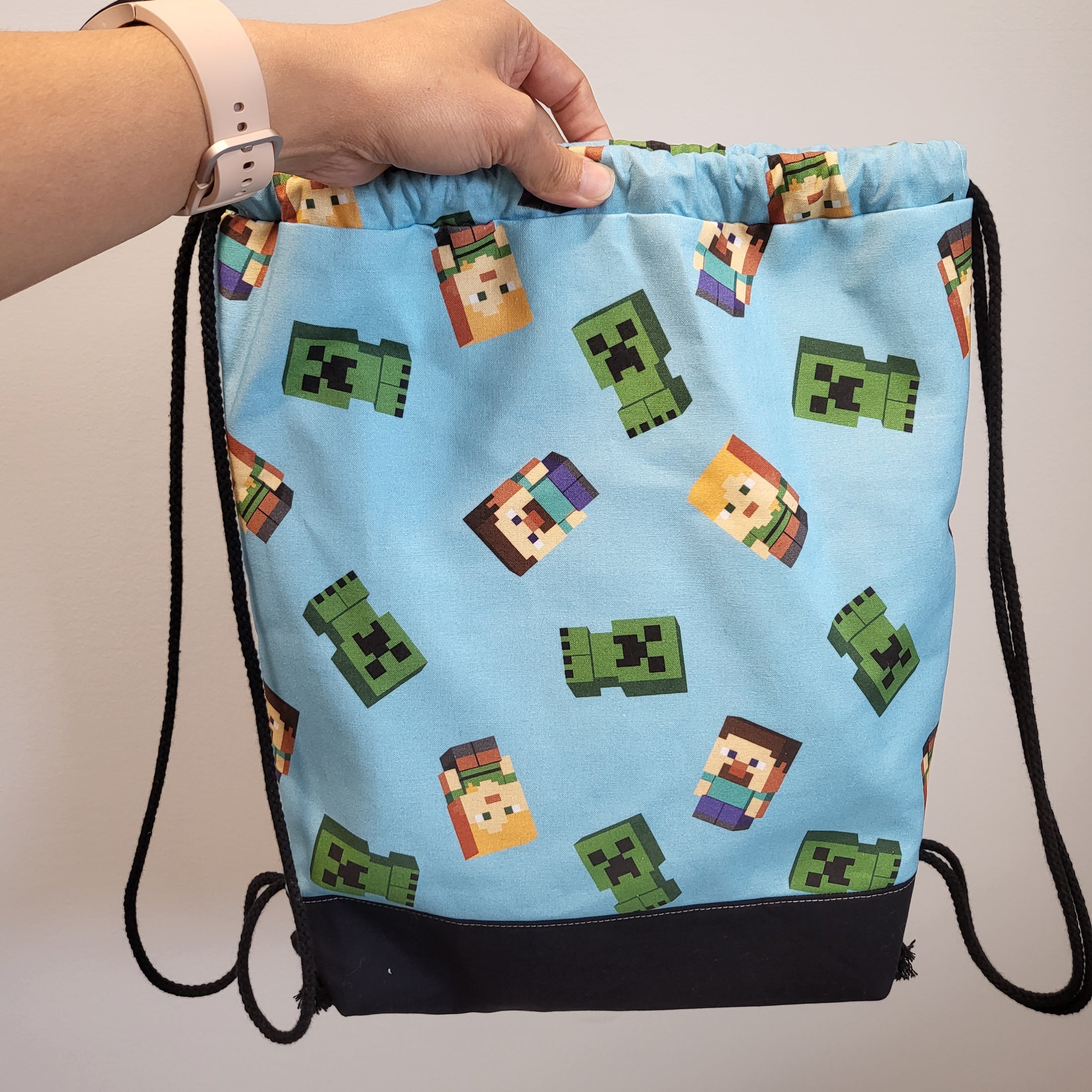 Back of the Minecraft themed drawstring backpack, uncinched, showing the characters Alex, Steve and Creeper.