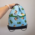 Load image into Gallery viewer, Minecraft inspired drawstring backpack with 2 exterior zipper pockets and black bottom. 

