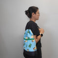 Load image into Gallery viewer, Person wearing the Minecraft drawstring backpack over the shoulder. 
