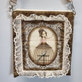 Load image into Gallery viewer, Close up view of the front of the purse with a lady wearing a birdcage skirt surrounded by lace. 
