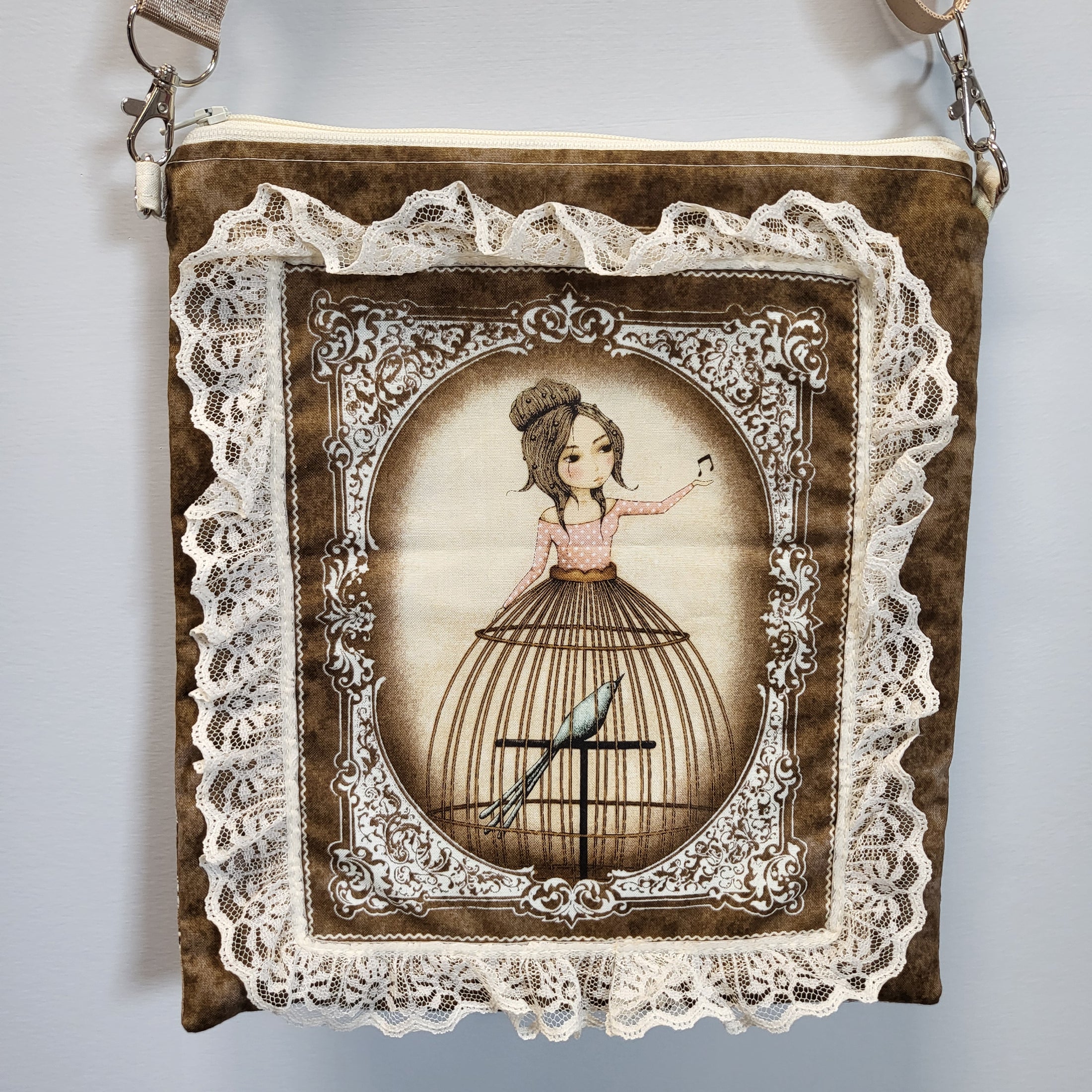 Close up view of the front of the purse with a lady wearing a birdcage skirt surrounded by lace. 