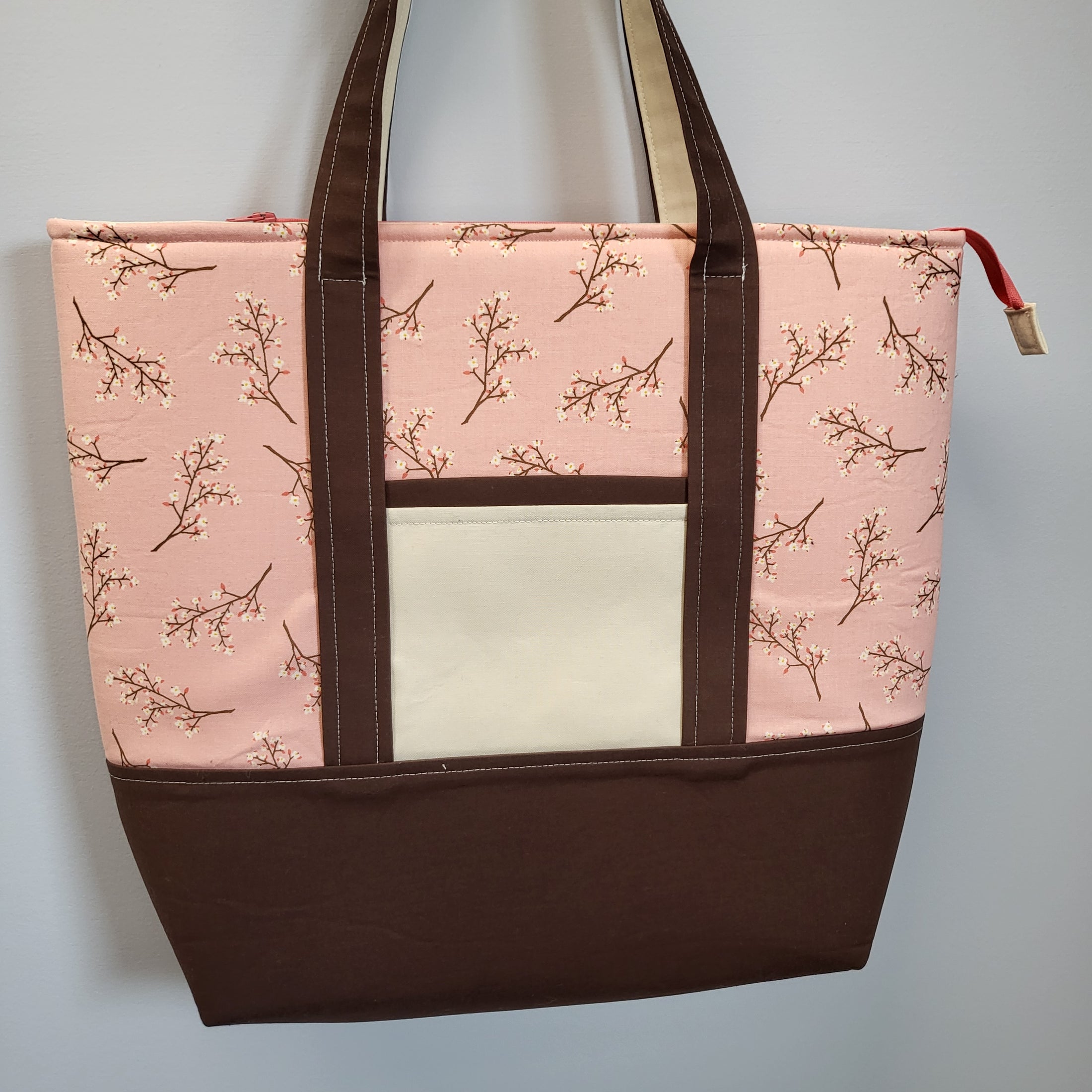 Padded cherry blossom tote bag with zippered main compartment and 2 exterior slip pockets. 