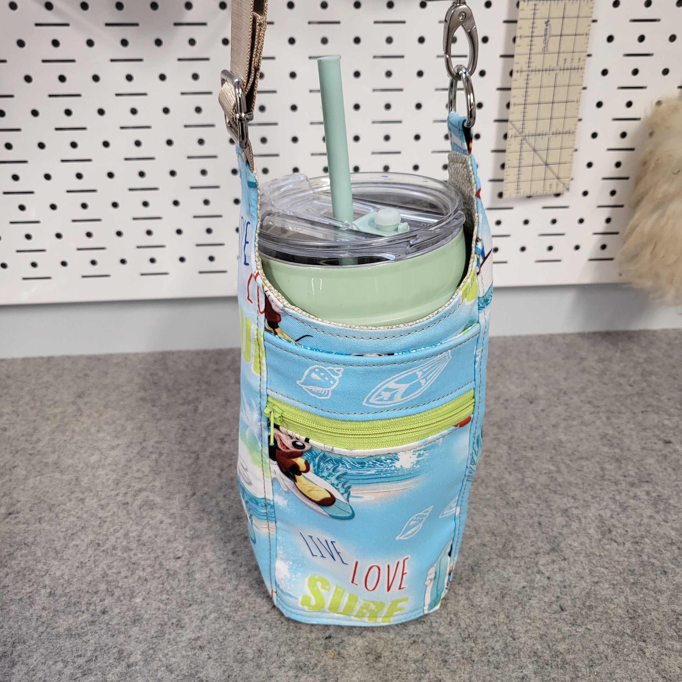 Blue and green drink carrier bag holding a thermos. 