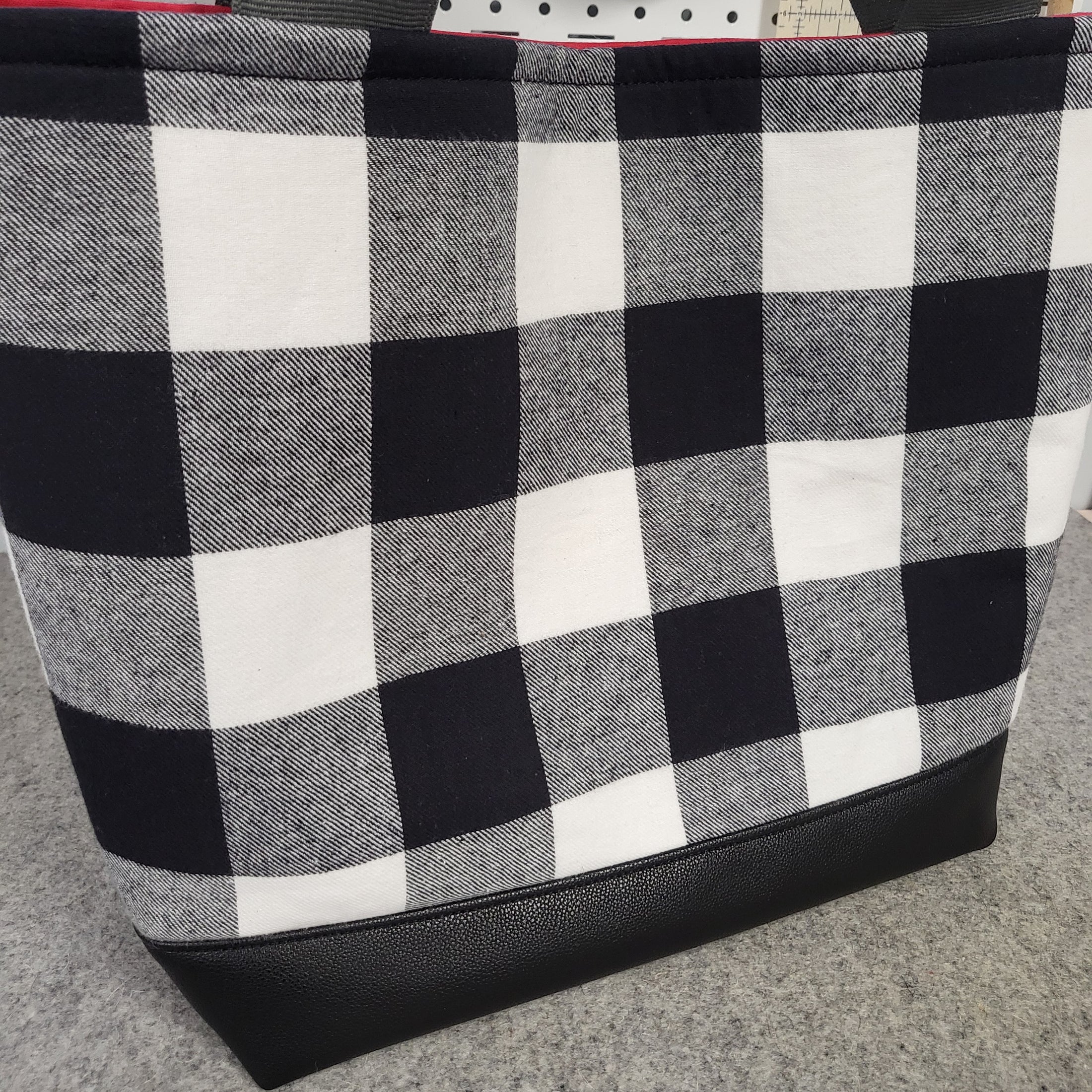 Black and white flannel tote bag with black bottom and gray handles.