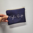 Load image into Gallery viewer, Swiftie zipper pouch with a blue/black background and Taylor Swift's signature in white on the back. 
