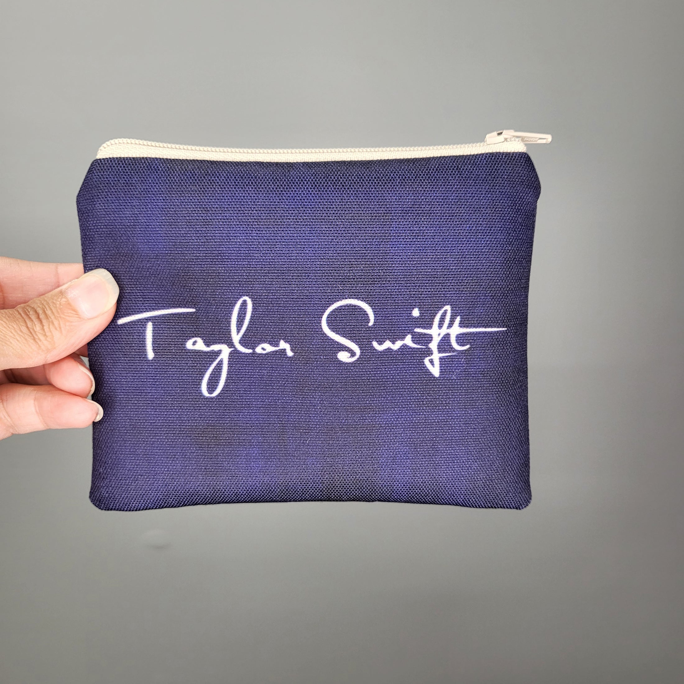 Back of the Swiftie zipper pouch showing Taylor Swift's signature in white on a dark blue background. 