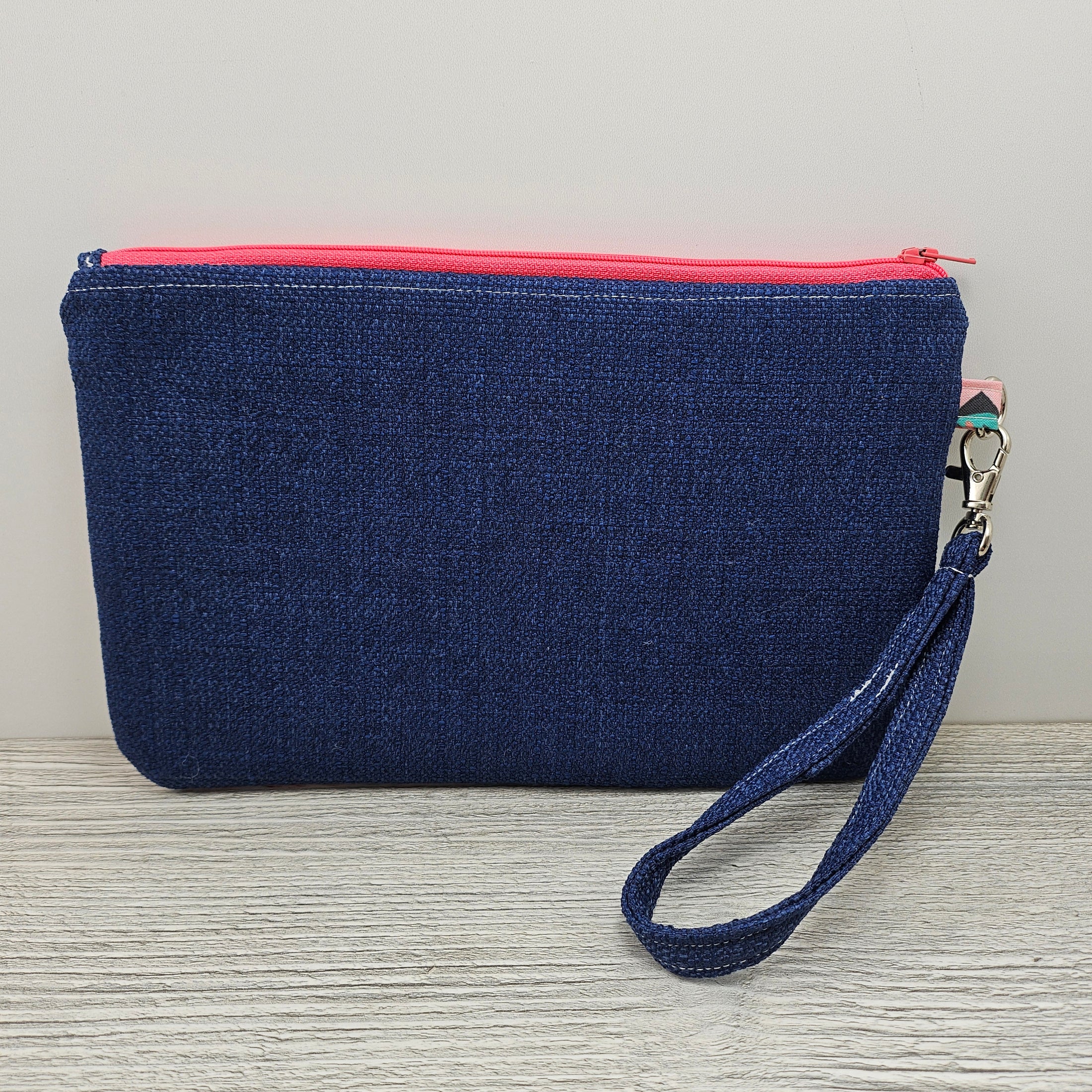 Blue back, pink zipper and detachable wristlet strap. 