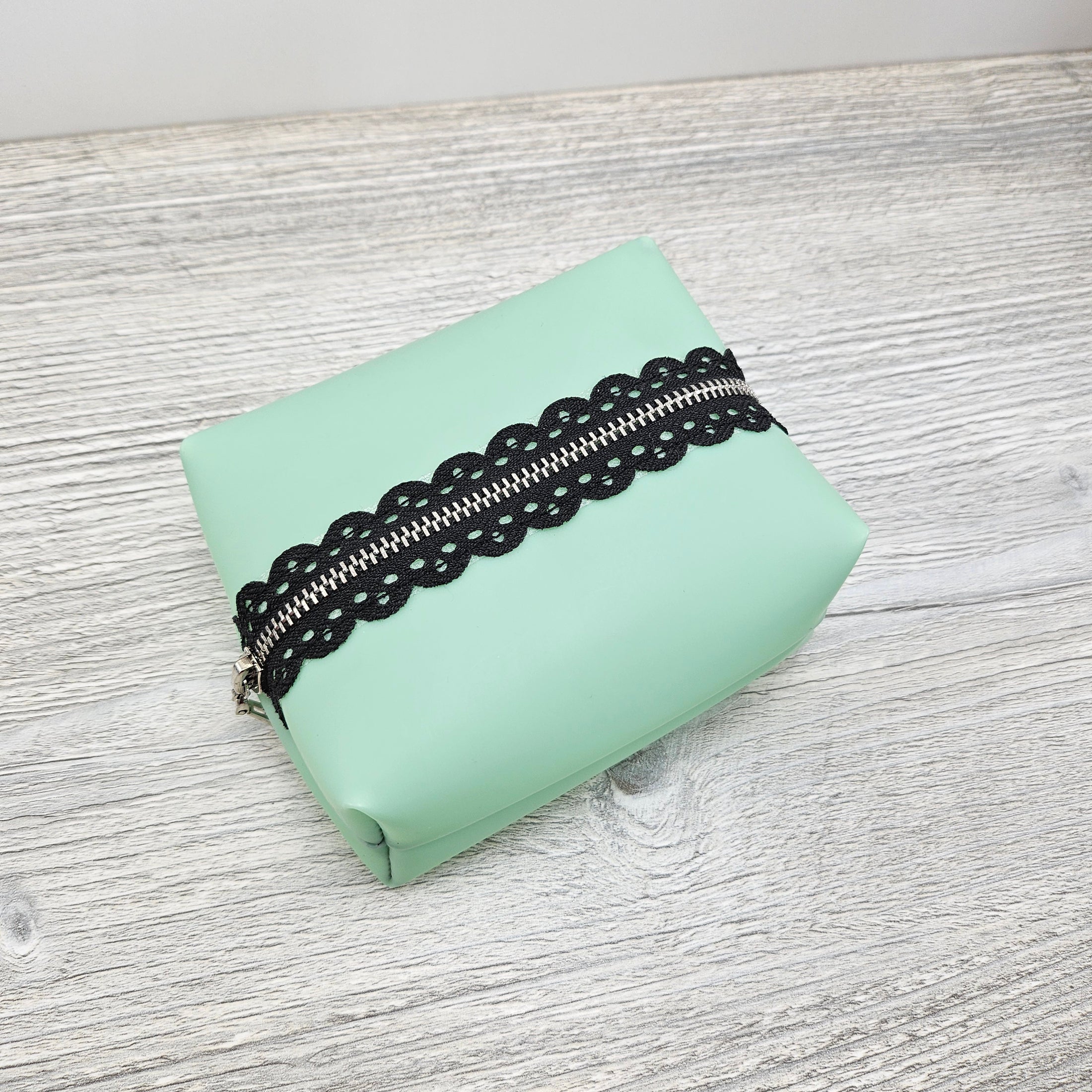 Mint green boxy pouch with black lace metal zipper.