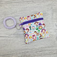 Load image into Gallery viewer, Mini vinyl zipper pouch featuring disney characters with a stretchy bracelet so you can wear it on your wrist. 
