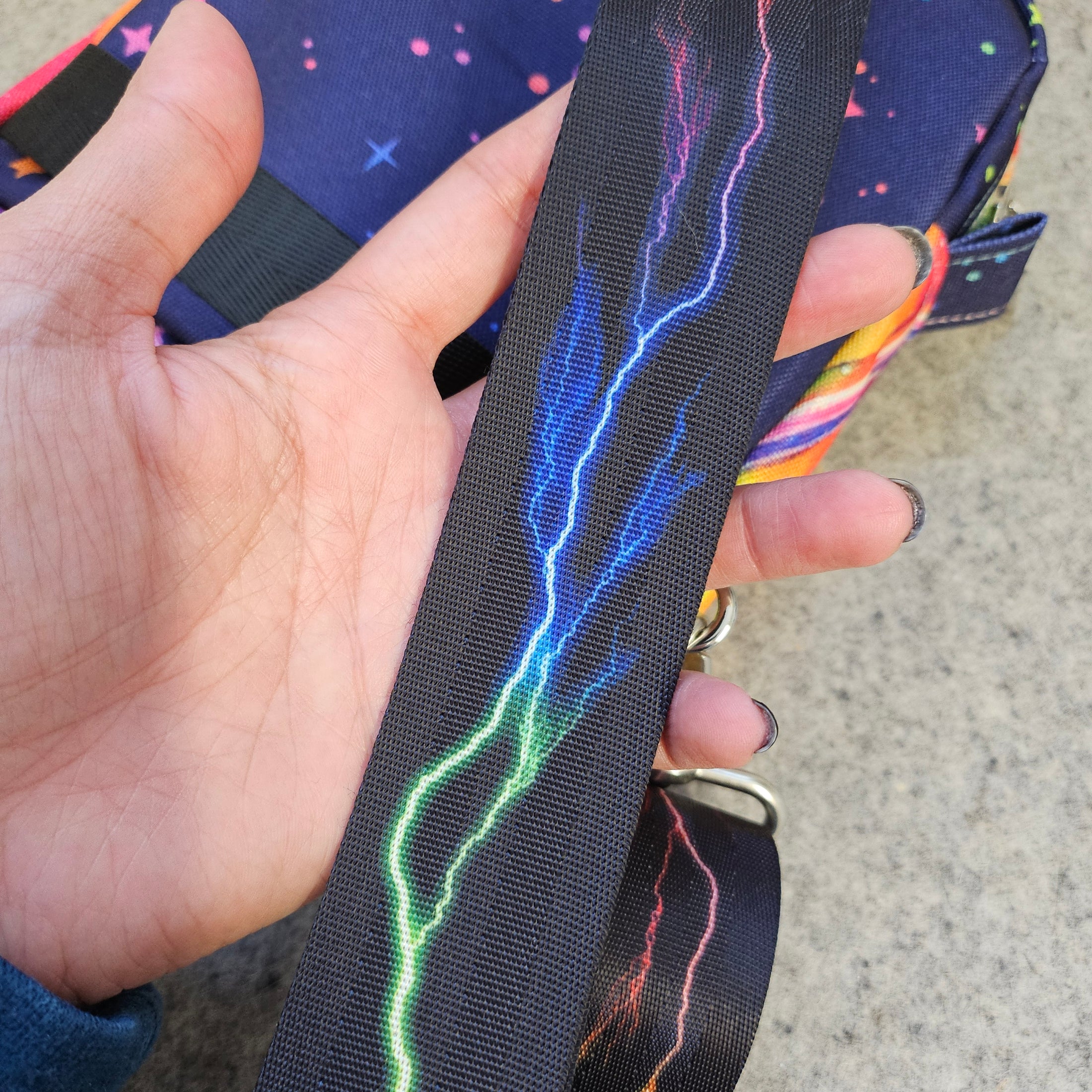 Black strap on the Sailor Moon inspired sling bag that is detachable, adjustable and features a rainbow colored lightning.