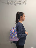 Load image into Gallery viewer, Wearing The Little Mermaid drawstring backpack on one shoulder. 
