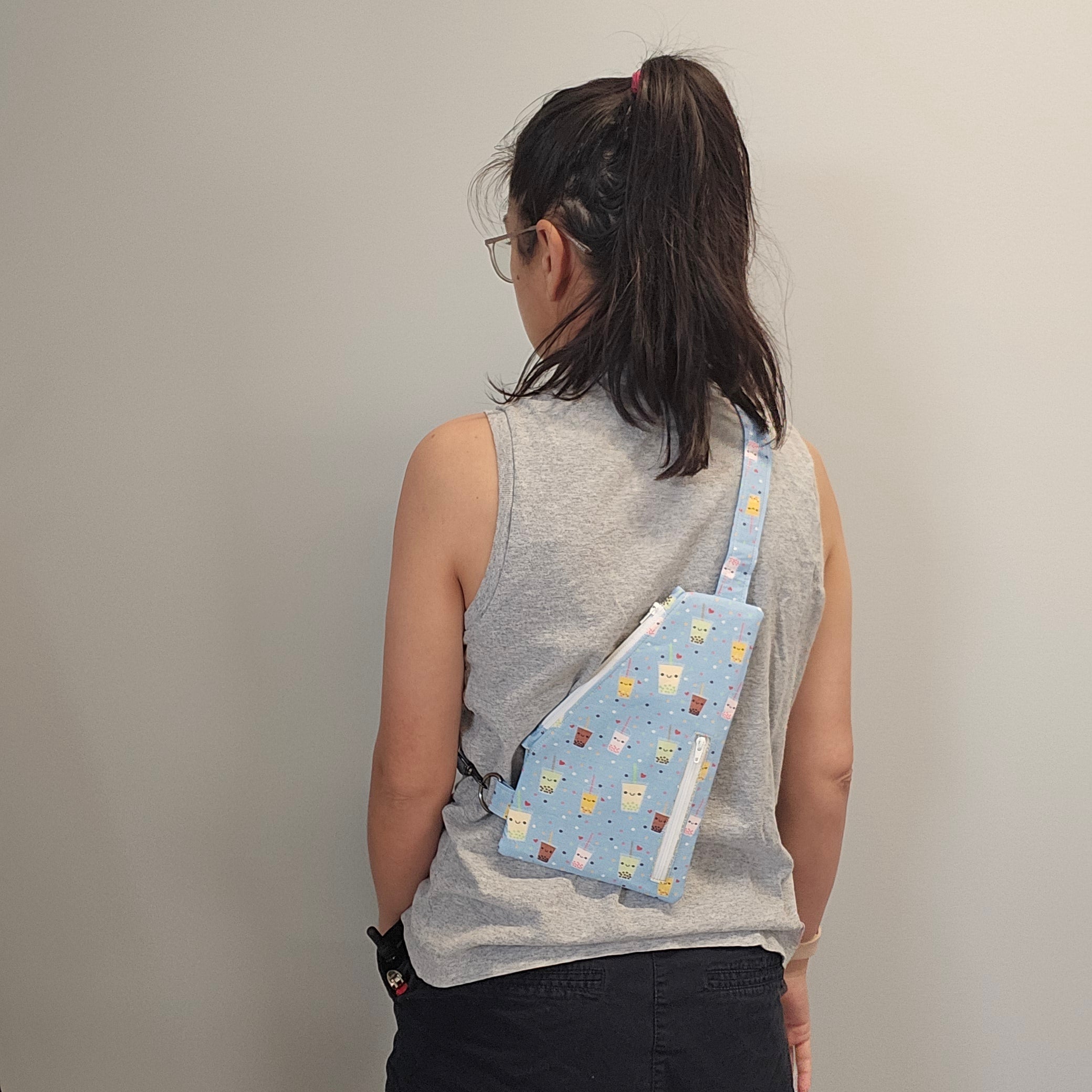 Person wearing the light blue bubble tea sling bag on their back.