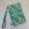 Load image into Gallery viewer, Green patterned clutch with a wrist strap on a gray surface
