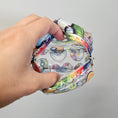 Load image into Gallery viewer, Colorful patterned coin purse held by a hand against a plain background
