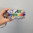 Load image into Gallery viewer, Colorful patterned pouch held in a hand against a gray background
