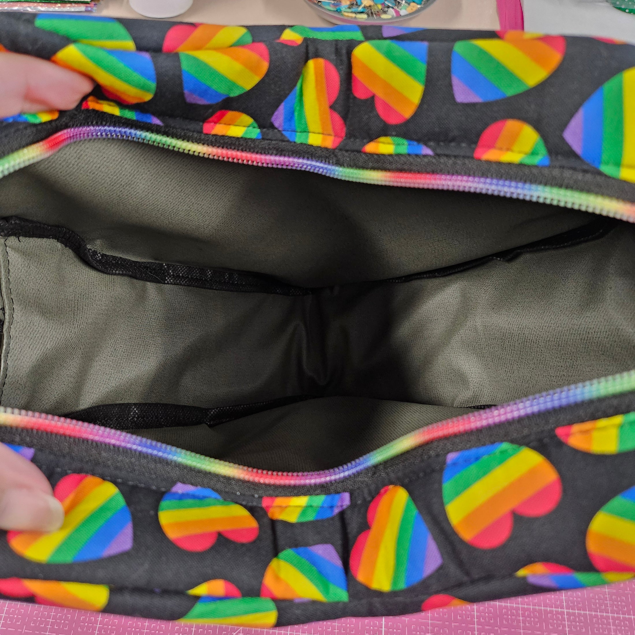 Black bag with rainbow heart pattern on a pink background