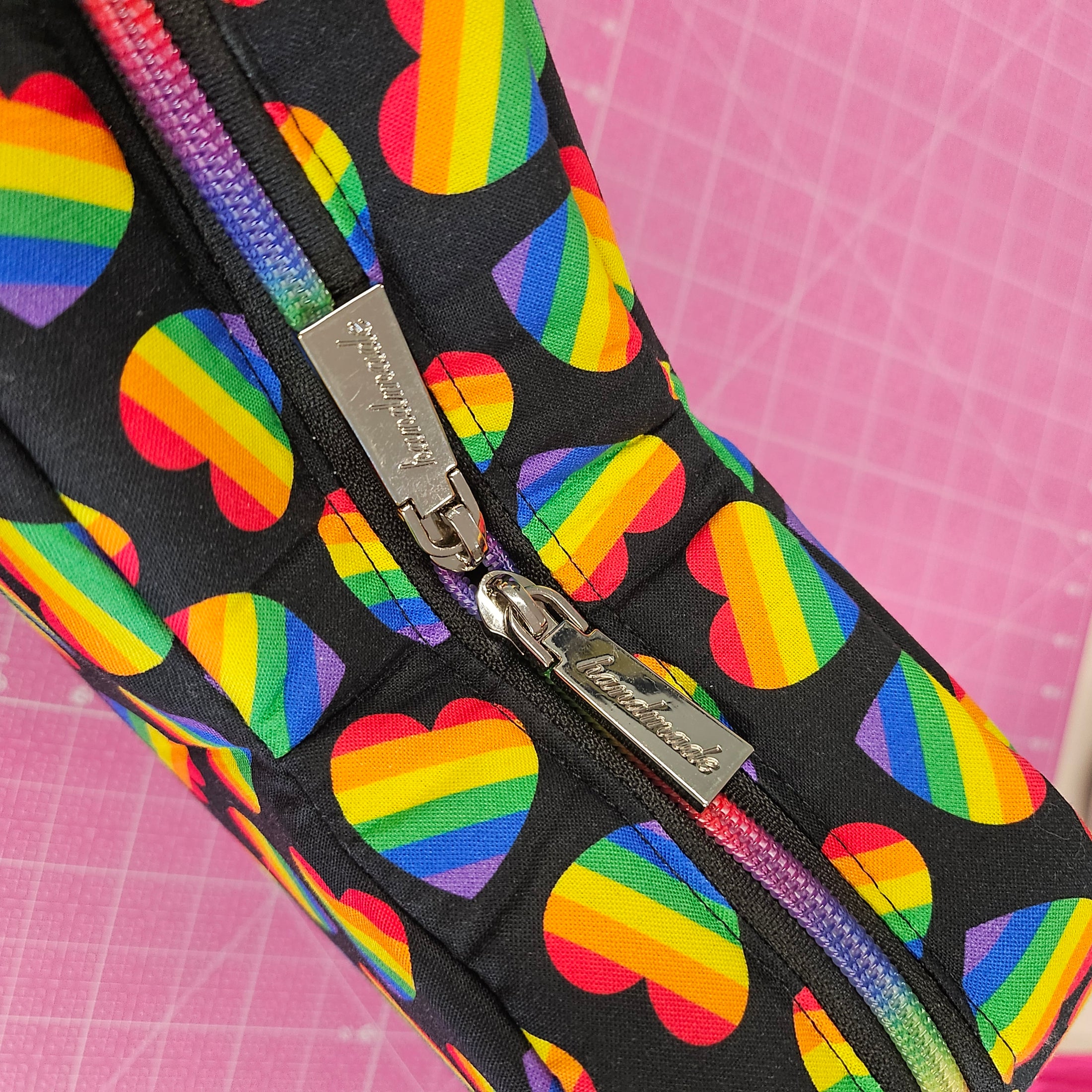Pouch with rainbow heart pattern on a pink grid background