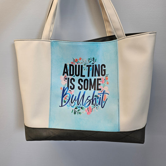 Bag with text 'ADULTING IS SOME B****H' on a light blue background