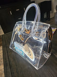 Load image into Gallery viewer, Clear birkin bag sitting on a dark brown table.

